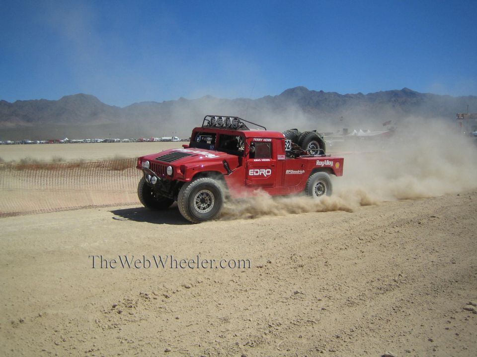 Red Hummer H1 off-road race truck sliding through desert dust
