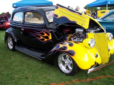1972 Ford Ranchero - A custom hot rod with flame graphics and an exposed engine is displayed at an outdoor event.
