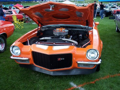 1972 Ford Ranchero - An orange 1970s Chevrolet Camaro Z28 is displayed with its hood open at an outdoor event.