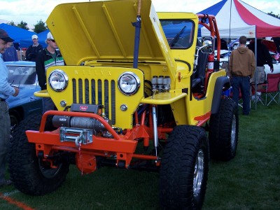1972 Ford Ranchero - A bright yellow Jeep with an orange winch and bumper sits on display with its hood open.