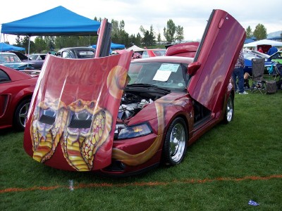 1972 Ford Ranchero - Customized red coupe displays custom cobra graphics on the hood and butterfly doors open at an outdoor car show.