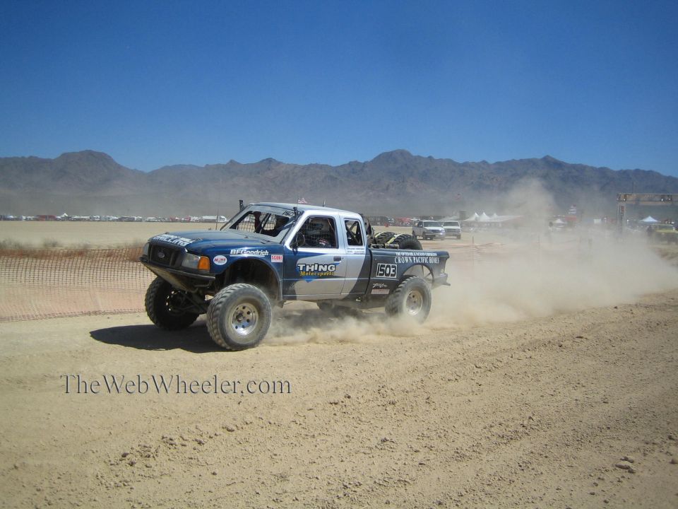 White and blue off-road race truck racing on a desert track