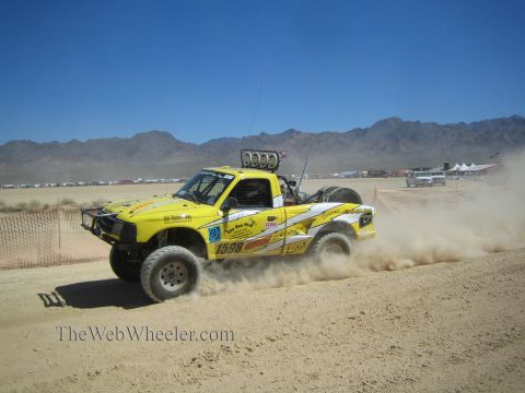 1990 Ford Bronco - yellow off-road race truck numbered 1598 races through a cloud of dust on a flat desert course.