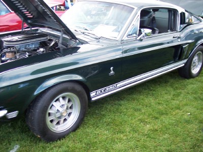 1972 Ford Ranchero - A dark green 1968 Shelby GT350 is displayed with its hood open, revealing the engine and a prominent side stripe.