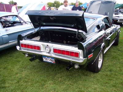 1972 Ford Ranchero - Rear view of a dark green 1969 Ford Mustang Mach 1 with its trunk open at an outdoor car show.