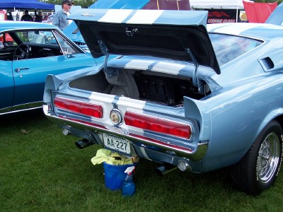 1972 Ford Ranchero - A light blue 1969 Ford Mustang Mach 1 is shown from the rear with its trunk open, prominent racing stripes.
