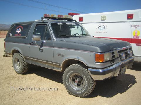1990 Ford Bronco - gray lifted Ford Bronco marked Rescue sits on a dirt lot beside a white ambulance.