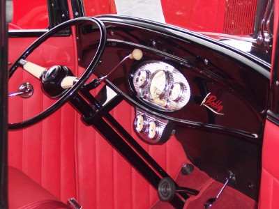 1972 Ford Ranchero - The interior of a classic car features a black dashboard with chrome gauges and red seating.