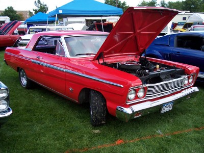 1972 Ford Ranchero - A red 1965 Ford Fairlane 500 coupe is displayed with its hood open at an outdoor car show.