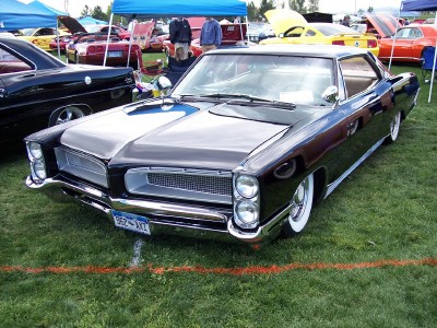 1972 Ford Ranchero - A classic black sedan is displayed at an outdoor car show with other vehicles and tents visible.