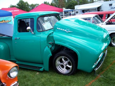 1972 Ford Ranchero - A teal 1956 Ford F-series pickup truck is displayed with its hood open, chrome wheels and other vehicles in the background.