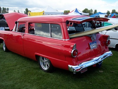 1972 Ford Ranchero - A red 1955 Ford station wagon is parked on grass with a surfboard loaded in the back.