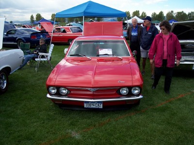 1972 Ford Ranchero - A red 1965 Chevrolet Corvair coupe is displayed at an outdoor car show with its hood open.