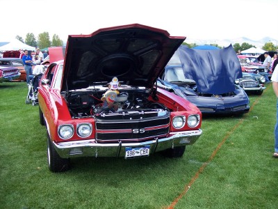 1972 Ford Ranchero - A red muscle car with its hood open is displayed on a grassy field next to other vehicles.