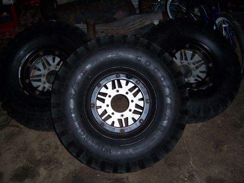 1983 Ford Bronco - A set of off-road tires and wheels are displayed indoors, possibly for sale or storage.