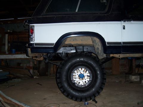 1983 Ford Bronco - Rear view of a 1983 Ford Bronco with a large off-road tire and silver beadlock wheel.