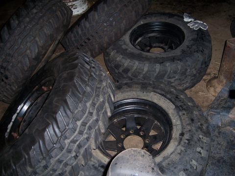 1983 Ford Bronco - Several off-road tires and rims are piled up, with one tire showing 'MILITARY-02' text.