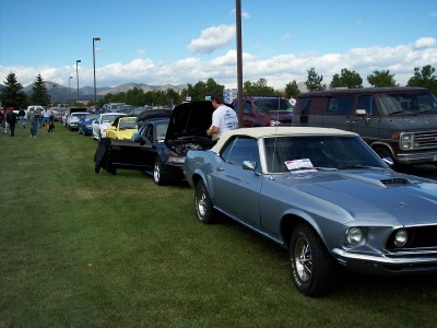 1972 Ford Ranchero - A line of cars are parked on a grassy field under a partly cloudy sky.