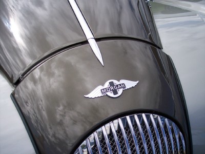 1972 Ford Ranchero - Close-up of a Morgan car's hood emblem and grille, reflecting the sky.