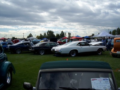 1972 Ford Ranchero - Outdoor car show features multiple classic vehicles under a cloudy sky.