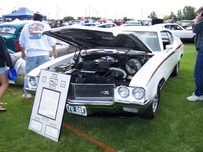 1972 Ford Ranchero - A white 1970 Buick GSX is displayed with its hood open, revealing the engine compartment, at an outdoor car show.