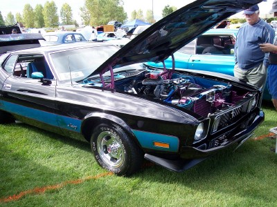 1972 Ford Ranchero - A black 1970s coupe with blue racing stripes is displayed with its hood open, revealing the engine bay.