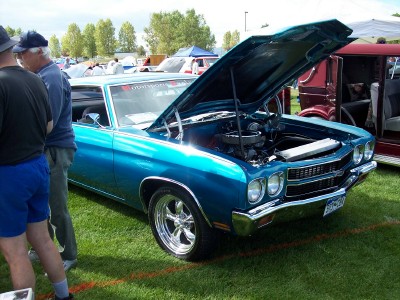 1972 Ford Ranchero - A bright blue coupe with its hood raised to reveal the engine, parked on a grassy field at an outdoor event.