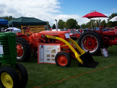 1972 Ford Ranchero - An orange tractor with a yellow front loader is displayed next to a green tractor at an outdoor event.
