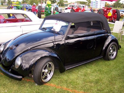 1972 Ford Ranchero - A black convertible Volkswagen Beetle is parked on grass at an outdoor event with other vehicles and people in the background.
