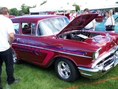1972 Ford Ranchero - A classic red sedan, likely a 1957 model, is displayed with its hood open at an outdoor car show.