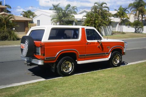 1982 Ford Bronco - Orange and white 1982 Ford Bronco with a spare tire mounted on the back.