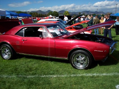 1972 Ford Ranchero - A red 1967 Firebird coupe is displayed with its hood open at a car show.