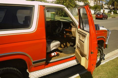 1982 Ford Bronco - The SUV's interior shows a fire extinguisher mounted near the driver's side floor.