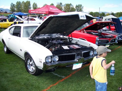 1972 Ford Ranchero - A white 1970 Oldsmobile 442 is displayed with its hood open at an outdoor car show.