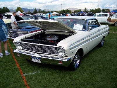 1972 Ford Ranchero - A white 1964 Ford Falcon coupe is displayed with its hood open at an outdoor car show.