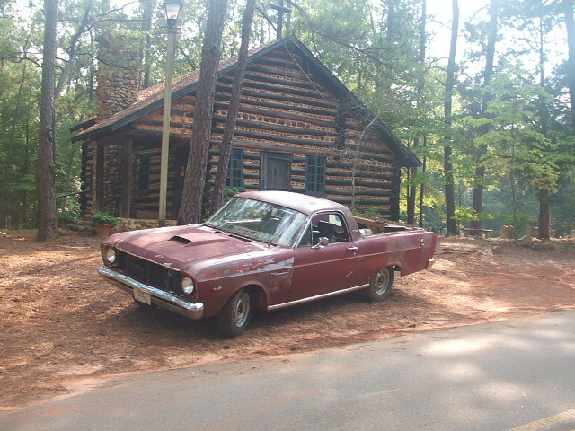 Maroon 1966 Ford Ranchero parked in front of a log cabin