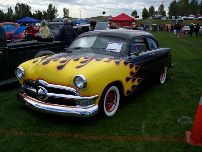 1972 Ford Ranchero - A customized 1950 Ford sedan with flame graphics is displayed on a grassy field.