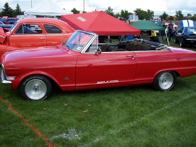 1972 Ford Ranchero - A red convertible with a white top is parked on grass at an outdoor event.