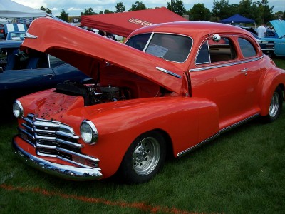 1972 Ford Ranchero - Classic red coupe with hood open at a car show, likely from the 1940s.