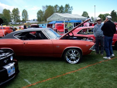 1972 Ford Ranchero - A classic orange muscle car, likely a 1969 model, is displayed with its hood open at an outdoor car show.