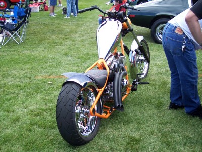 1972 Ford Ranchero - A custom motorcycle with a distinctive orange frame and a large rear tire is displayed on a grassy field.