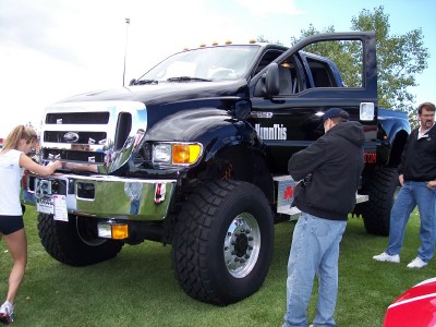 1972 Ford Ranchero - A black Ford F-650 truck is displayed with its doors open, attracting attention from onlookers.