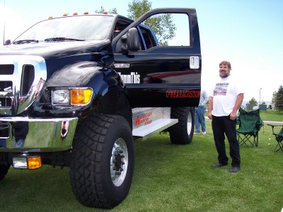 1972 Ford Ranchero - A black Ford F-650 truck is parked on grass with its door open, and a man stands beside it.