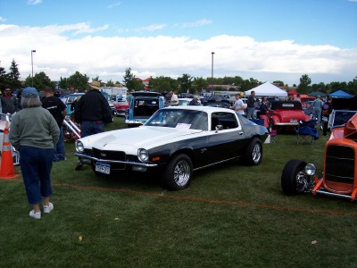1972 Ford Ranchero - A two-tone Chevrolet Camaro is displayed at an outdoor car show with other vehicles and people around.