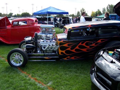 1972 Ford Ranchero - A custom hot rod with a prominent engine and flame graphics is displayed at an outdoor event.