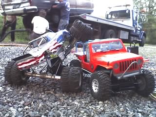 1976 GMC C/K Pickup - RC rock crawlers with detailed bodies and large tires are positioned on a gravel surface.