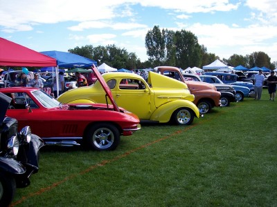 1972 Ford Ranchero - Several vintage vehicles are lined up on a grassy field under a partly cloudy sky at a car show.