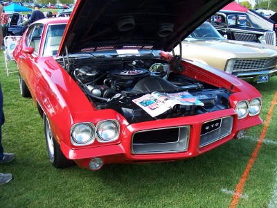 1972 Ford Ranchero - A bright red 1970 Pontiac GTO is displayed with its hood open, revealing the engine and a magazine on top.
