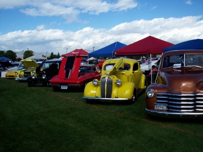 1972 Ford Ranchero - A variety of vintage automobiles are displayed on a grassy field under tents on a partly cloudy day.