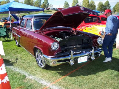1972 Ford Ranchero - A classic red sedan, possibly a 1954 model, is displayed with its hood open, its engine and chrome wheels.